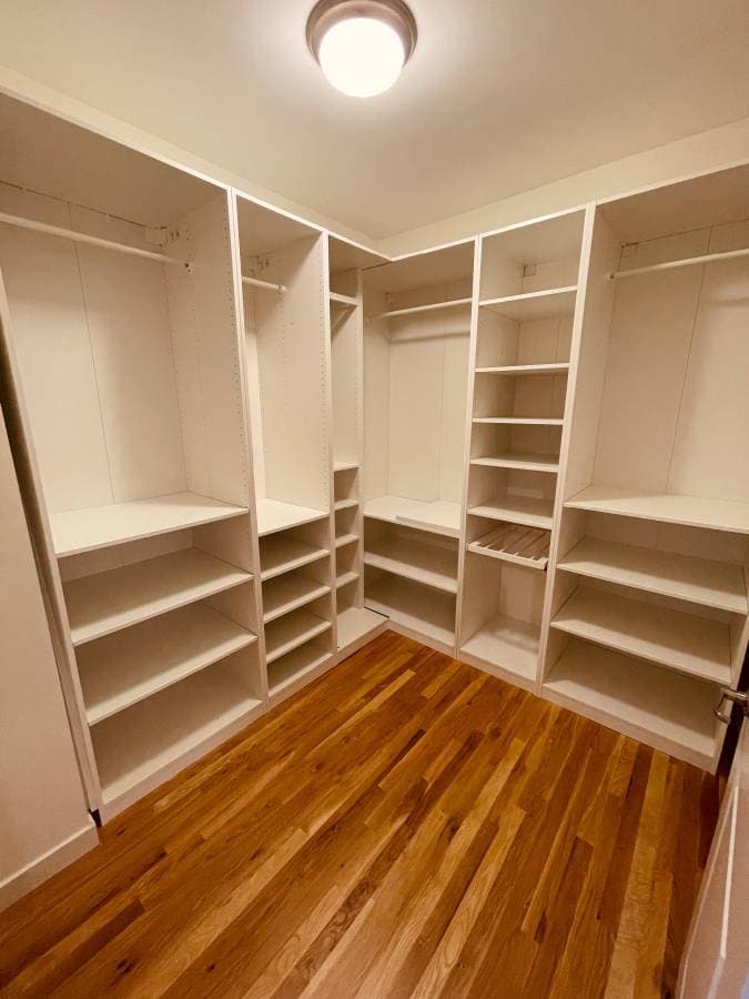 Custom walk-in closet installation with built-in shelving and wood flooring
